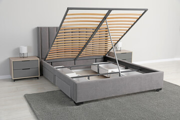 Comfortable bed with storage space for bedding under lifted slatted base in room