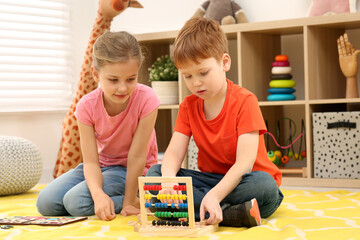 Children playing with math game kit on floor in room. Learning mathematics with fun