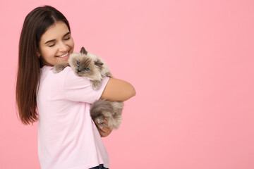 Happy woman hugging her cute cat on pink background, space for text