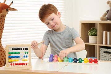 Little boy playing with Educational game Fishing for Numbers at desk in room. Learning mathematics with fun