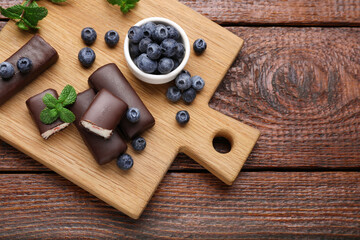 Delicious glazed curd snacks with fresh blueberries and mint on wooden table, top view. Space for...