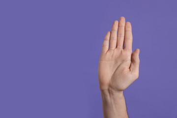 Naklejka premium Man giving high five on purple background, closeup of hand. Space for text