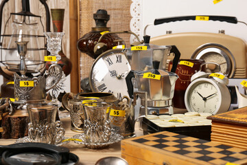 Many different items on wooden table indoors. Garage sale