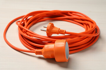 Extension cord on white wooden floor, closeup. Electrician's equipment