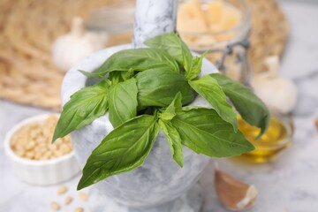 Fresh basil in mortar on table, closeup. Ingredients for pesto sauce