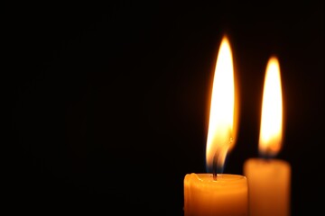 Burning candles on black background, closeup. Space for text