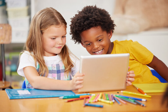 Kids love to learn. Shot of two preschool students looking at something on a digital tablet together.