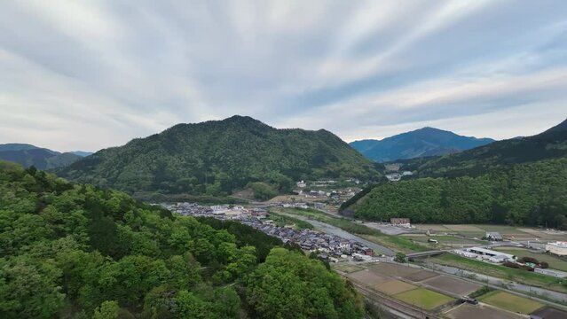 Flying over green hillside to reveal small town in rural mountain landscape