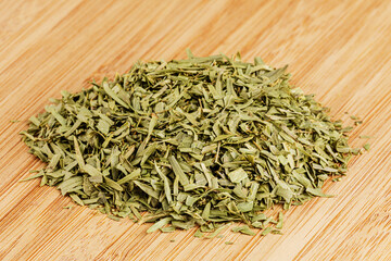 Dried Tarragon Leaves isolated on a wooden cutting board
