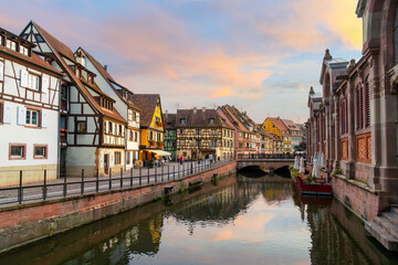 Fototapeta na wymiar Picturesque half timber buildings across from the riverfront Marché Couvert covered market at sunset along the Lauch River in the Petite Venice area of Colmar, France.