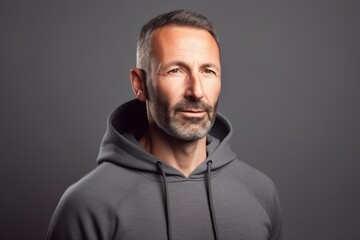 Fototapeta premium Portrait of a handsome middle-aged man in a gray hoodie on a gray background