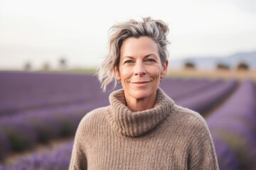 Fototapeta na wymiar Portrait of smiling mature woman standing in lavender field on a sunny day