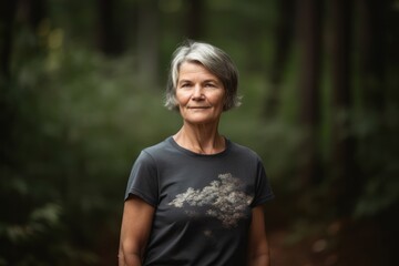 Portrait of a smiling senior woman standing in the forest. Looking at camera.