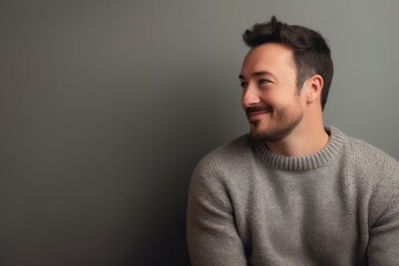 Young handsome man in a grey sweater on a gray background. Copy space.
