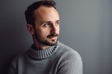 Portrait of a handsome young man in sweater on grey background.