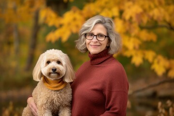 Portrait of a senior woman with a dog in autumn park.