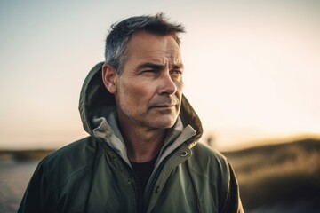 Portrait of a handsome middle-aged man in a green jacket on the beach