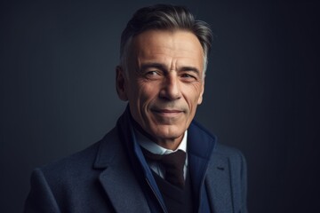 Portrait of mature man in suit looking at camera on grey background