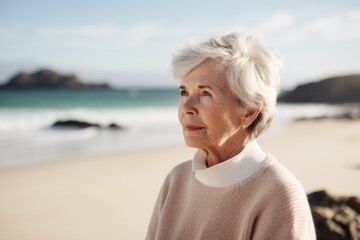 Fototapeta premium Portrait of happy senior woman standing on beach at the day time