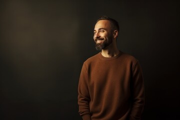 Obraz premium Handsome bearded man in a brown pullover on a dark background