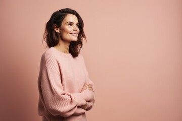 Obraz premium Portrait of a smiling young woman standing with arms crossed isolated over pink background