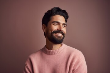 Fototapeta premium Portrait of a handsome young bearded Indian man in a pink sweater.