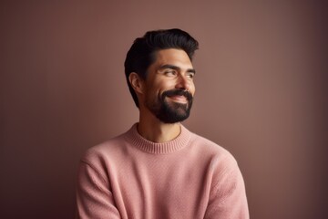 Obraz premium Portrait of a handsome Indian man in a pink sweater on a brown background