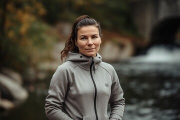 Portrait of a beautiful young woman in sportswear standing by the river.
