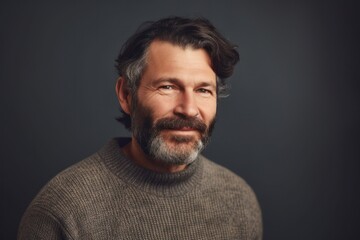 Portrait of a bearded middle-aged man in a gray sweater on a dark background