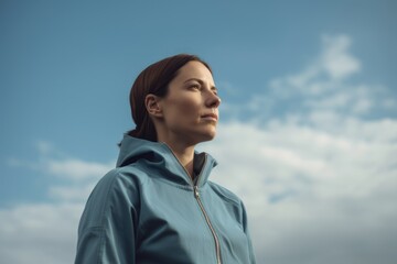 Portrait of a young woman in a blue jacket against the sky