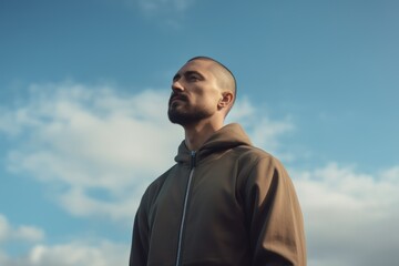 Handsome young man in sportswear posing against blue sky