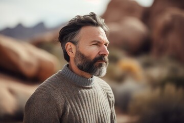 Portrait of a bearded man in the desert, looking away.