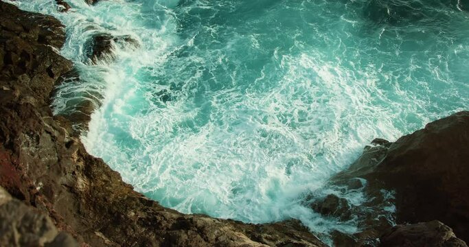 Rough sea waves foaming on rocky shore. Raging ocean turquoise water.