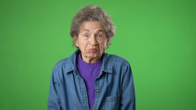 Portrait of happy elderly senior old woman with wrinkled skin and grey hair shrugging shoulders and gesturing I do not know isolated on green screen background.