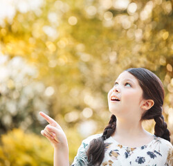 Young caucasian girl pointing in a direction in a forest while smiling outside. Young caucasian girl pointing in a direction in a forest while smiling outside.