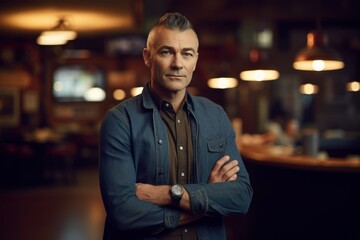 Portrait of handsome mature man standing with arms crossed in cafe.