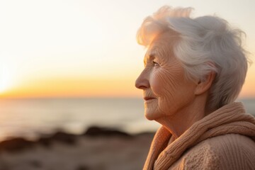 Fototapeta na wymiar Portrait of senior woman looking away while standing on beach at sunset