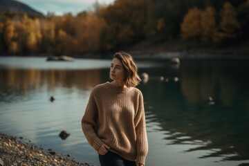 Portrait of a young woman in a sweater on the shore of a lake.