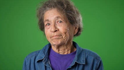 Closeup portrait of happy smiling elderly senior old woman with wrinkled skin and grey hair on green screen background.