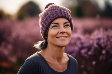 Portrait of a beautiful woman in a purple hat and a black sweater on a background of purple flowers