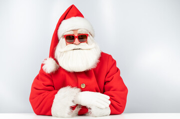 Portrait of santa claus sitting with his arms folded at a white table. 