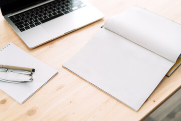Blank blank notepad with laptop on wooden table.