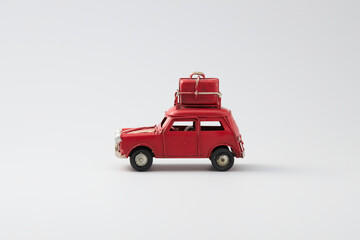 red vintage toy car with travel luggage on top, isolated on white background