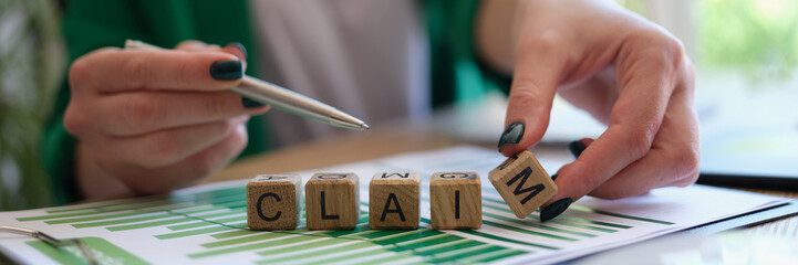 Woman pointing with pen on word claim and putting wooden cube