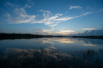 Colorful sunrise cloudscape reflected in calm water of Nine Mile Pond in Everglades National Park, Florida.