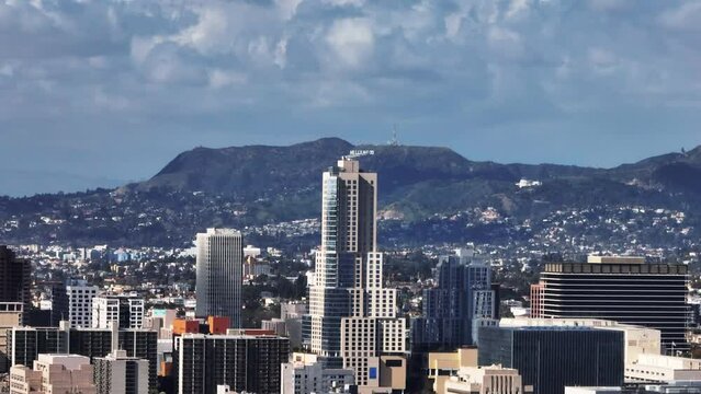 Zoomed shot of high rise office towers in city and Hollywood Sign in hills above city in distance. Los Angeles, California, USA