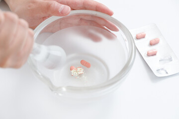 粉砕指示と薬剤師。乳鉢に錠剤があり、乳棒で砕いている © hikari_stock