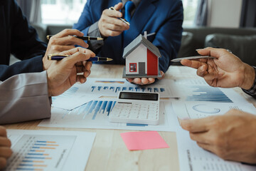 teamwork of business people at a meeting Analyze earnings charts and graphs by talking to a real estate agent at the office. House designs in savings plans for people's housing workplace strategy