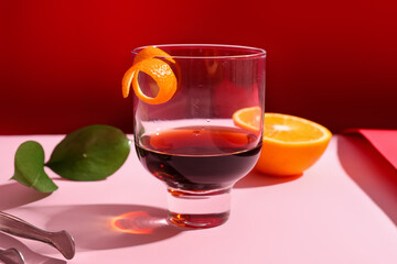 Glass of rum with orange on pink and red background