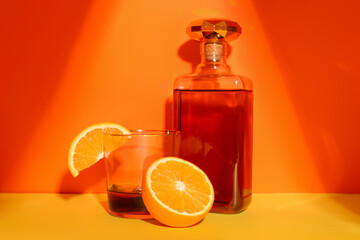 Glass of rum, bottle and orange on colorful background